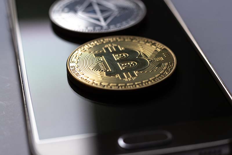 Blockchain and Cryptocurrency Image of physical bitcoin on phone